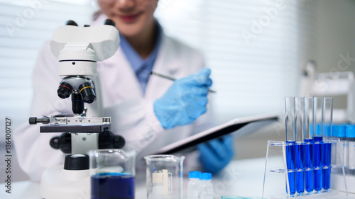 Tableau sur toile Asian adult scientist conducting laboratory research using microscope recording
