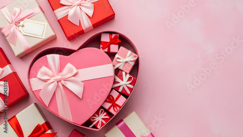 Pink gift box wrapped red ribbon bow with red hearts and confetti on pastel pink background. St Valentines Day holiday concept. Top view, flat lay, copy space.