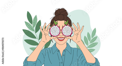 Playful portrait of a smiling woman holding two slices of dragon fruit over her eyes with tropical green leaves in the background.