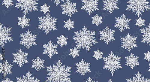 Elegant seamless winter pattern of detailed and intricate white snowflakes of various sizes scattered on a dark blue background.