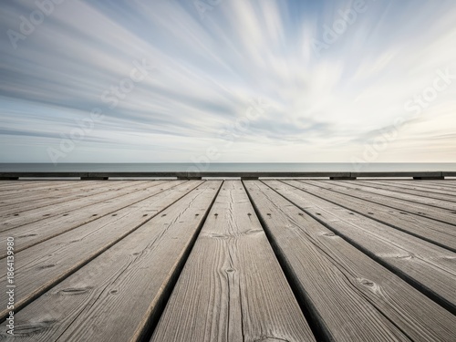 Long exposure view from a weathered wooden pier stretching towards the vast ocean under a dynamic sky