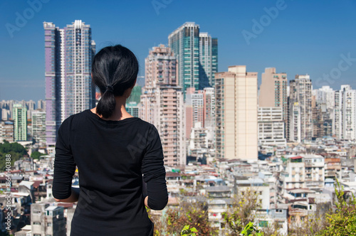 Photography a brunette woman overlooking the city of macau china on a sunny day