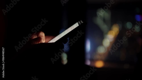 hand holding phone near window with city bokeh, fingertip interacting with glowing screen reflections on glass, soft neon highlights, focused closeup showing interface and notification glow