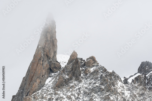 Dente del Gigante piercing through cold foggy sky in mont blanc