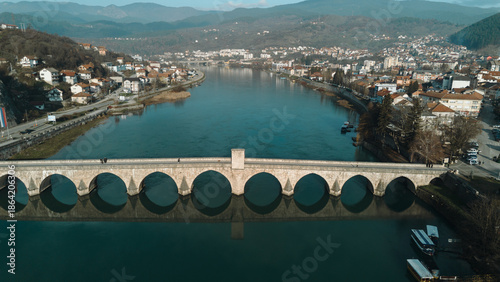 Aerial view of the historic Mehmed Pasha Sokolovic Bridge crossing the Drina River in Visegrad, Bosnia and Herzegovina. Timeless Ottoman architecture meets calm river landscape