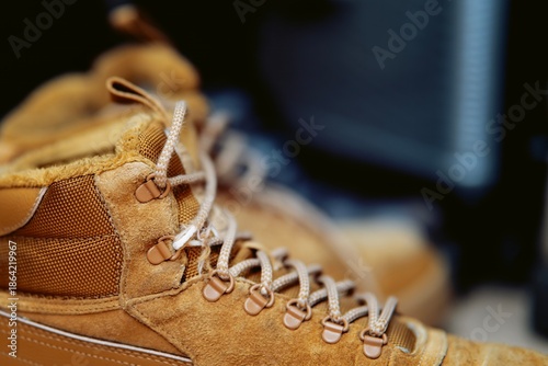 Yellow leather boot with frayed shoelace revealing inner white thread. Worn footwear and damage detail