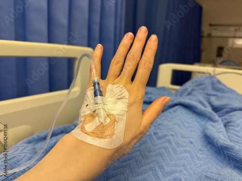 Patient Hand with IV Drip in Hospital Bed. Medical treatment, healthcare, hospitalization, recovery,  emergency and clinical care concept