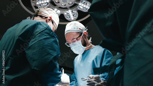 Fotografi Surgeons in sterile operating room, focused on intricate procedure, illuminated