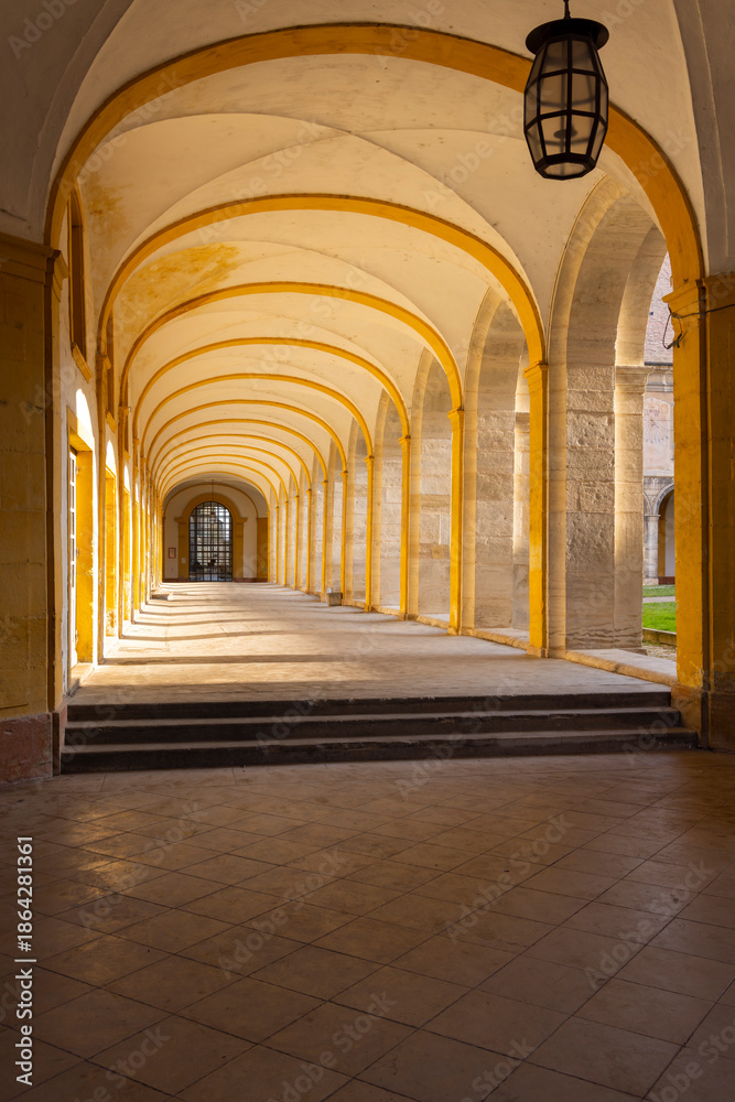 Fototapeta premium Arched cloister walking through light and shadow in Cluny