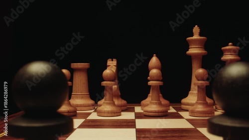Close up and dolly zoom macro cinematic shot of wooden chess pieces on board. Black and light pawn, king, queen, bishop and rook stand. Strategic scene with chess on chessboard and dark background.