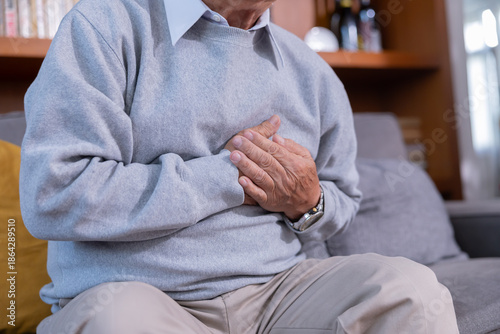Fotografie Elderly man grab his chest with hand suffer from chest pain in a living room