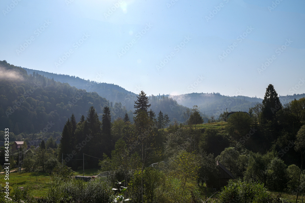 Fototapeta premium Serene landscape with misty morning fog over green meadow and mountains
