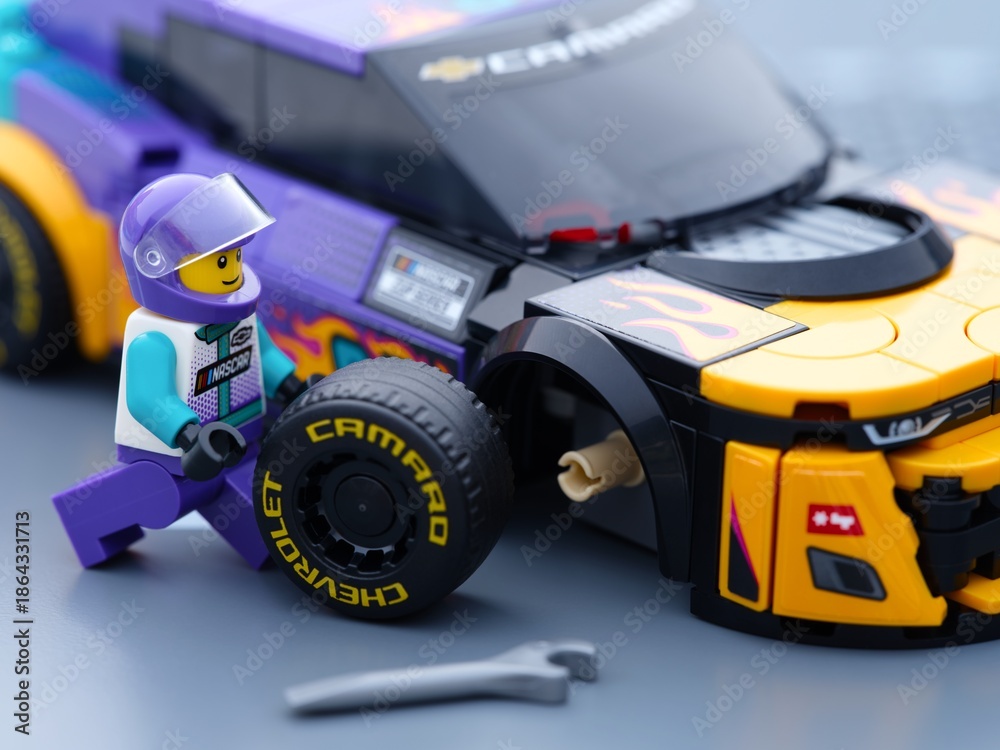 Fototapeta premium Tambov, Russian Federation - January 02, 2026 Lego driver minifigure changing wheel of his Lego NASCAR Next Gen Chevrolet Camaro ZL car. LEGO Speed Champions.