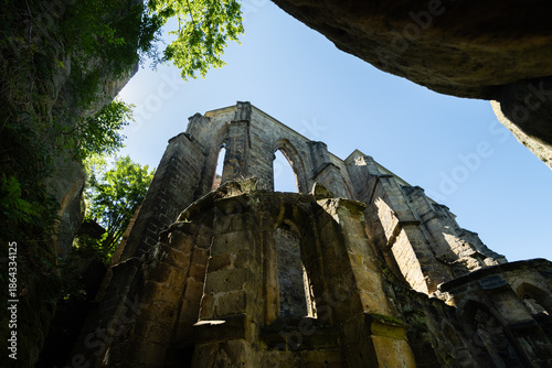 Obraz na płótnie Gothic arches towering amid green trees and blue sky in Oybin Monastery ruins on
