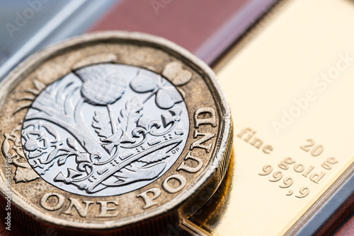 Gold bar and one pound coin macro close up showing bullion investment and wealth preservation concept. Stafford, United Kingdom, January 3, 2026,