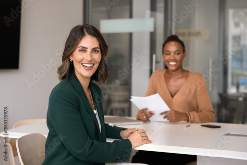 Obraz na plátně Happy confident Latin applicant woman sitting at meeting table with interviewer,