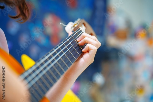Girl playing guitar and fingering chords on the fretboard on a bright day for practice. Music learning outdoors