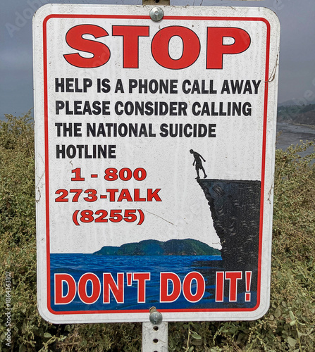 Slika na platnu A sign at the edge of a tall, steep cliff above the Pacific Ocean near Los Angeles, California, with a suicide prevention hotline number to call