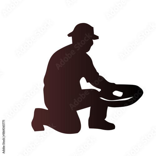 Silhouette of a prospector kneeling and panning for gold in a river.