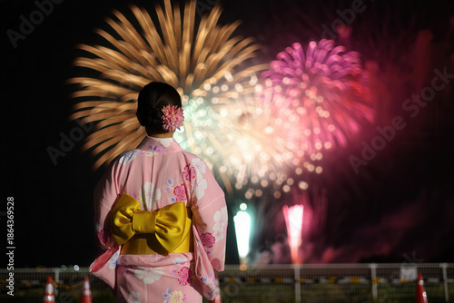 Rear view of Japanese woman in pink kimono watching fireworks display