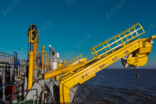 Slika na platnu Yellow hydraulic crane with lattice boom mounted on dredging vessel deck