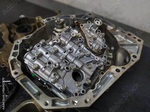 Internal view of an automatic gearbox housing showing the complex valve body and solenoids during an automotive transmission overhaul.