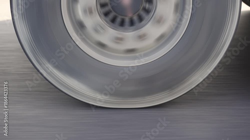 Authentic shot of spinning tires of semi trailer truck driving along a countryside road, closeup shot
