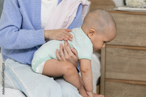 Tableau sur toile Careful mother burping little baby boy gently rubbing back to comfort gas pain a