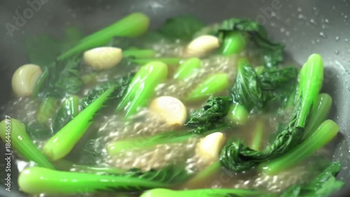 Fresh green vegetables with garlic cooking in a pan with steam and light