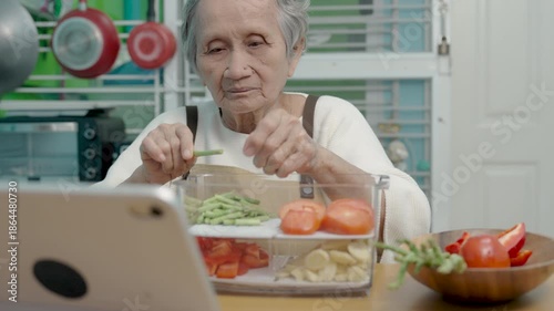 Seniors woman are cooking in their home kitchen and looking at digital tablets to learn how to cook.