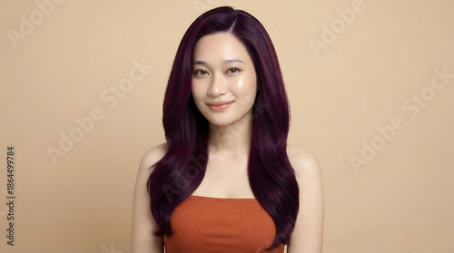 Wallpaper Mural A beautiful young Asian woman with long, wavy dark purple hair and a radiant smile, wearing an orange top against a beige background. Torontodigital.ca