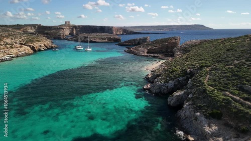 A beautiful low flyover along the blue lagoon with ships, Comino