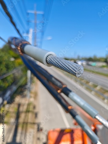 Close up detail of twisted aerial bundle cable texture showing black insulation and aluminum core for electric power distribution grid infrastructure background.