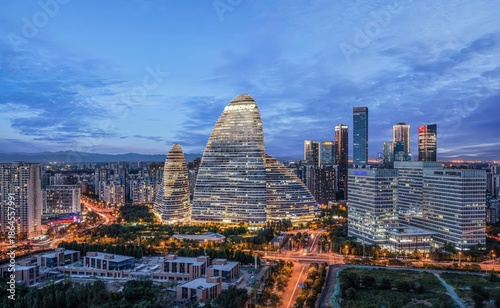 A stunning cityscape of Beijing's iconic Wangjing SOHO at dusk, showcasing modern architecture with vibrant city lights and a clear sky backdrop.