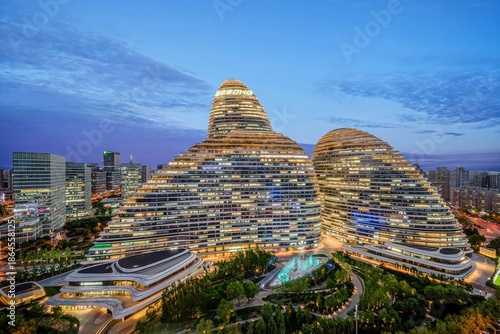 A stunning aerial view of the iconic Beijing Wangjing SOHO complex during twilight, showcasing modern architecture and urban lighting.