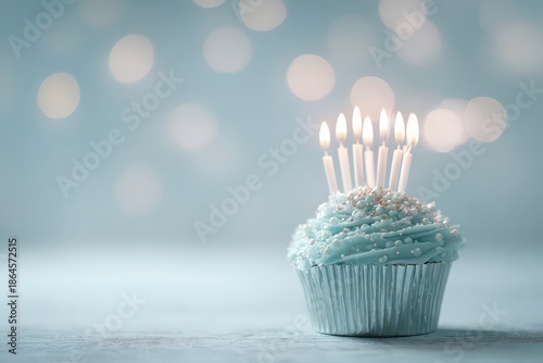 Pastel Blue Cupcake with Lit Candles on Light Surface and Bokeh Background Festive Celebration Sweet Treat Still Life Confection Bakery