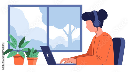 Woman working on laptop with headphones on, seated at a desk with plants by a window