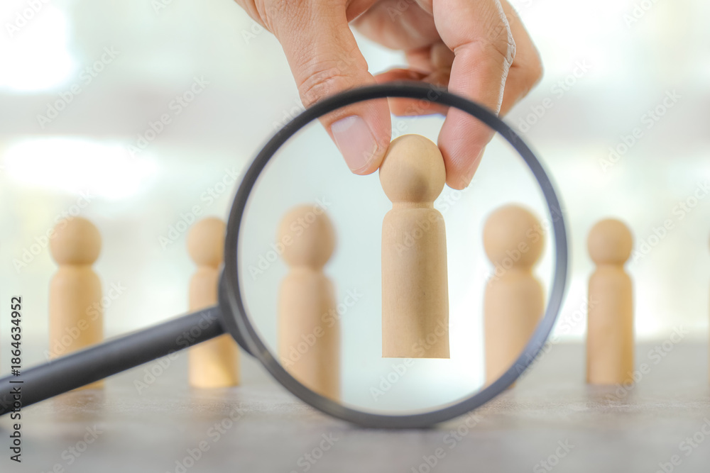Fototapeta premium Businessman's hand chooses wooden person stands for HR human resources personal leader training skill or leadership and challenge business team player and organization management teamwork.