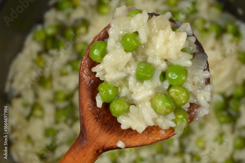 Tableau sur toile A close up shot of a wooden spoon holding a portion of creamy rice with green pe