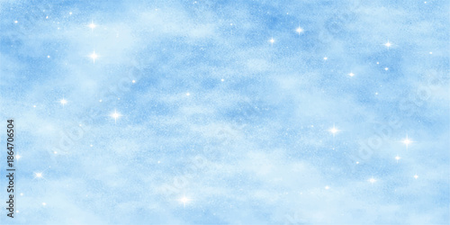 An abstract blue Christmas background features white snowflakes drifting through a beautiful clear sky with fluffy clouds and natural light to create a heavenly winter atmosphere