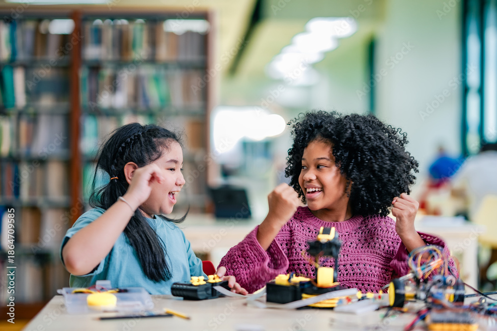 Fototapeta premium Two students show excitement after completing robotics activity together, surrounded by wires, robot parts, learning tools, STEM education, skills, happiness, motivation, classroom innovation moment.