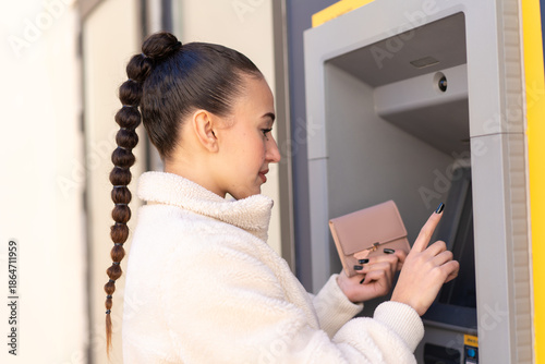 Young moroccan girl  at outdoors using an ATM