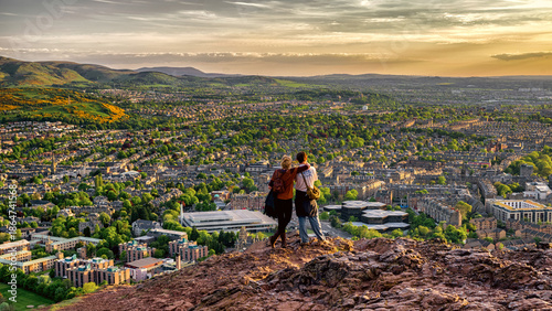 Romantic couple enjoying panoramic view over Edinburgh city from Arthurs Seat at sunset