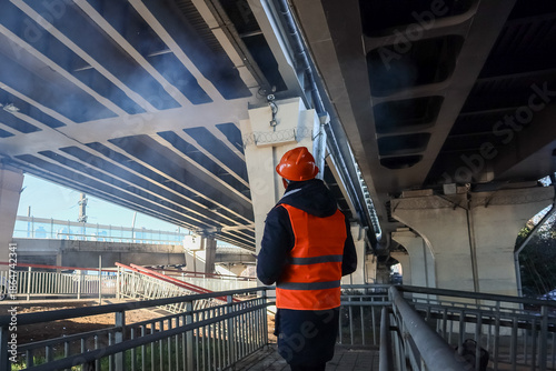 Obraz na plátne Back view of worker inspecting urban bridge base