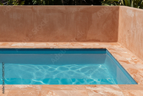Sunny, inviting pool with warm terracotta-colored surround.