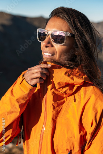 Thermally at ease outdoor hiking female adjusting collar in soft mountain light