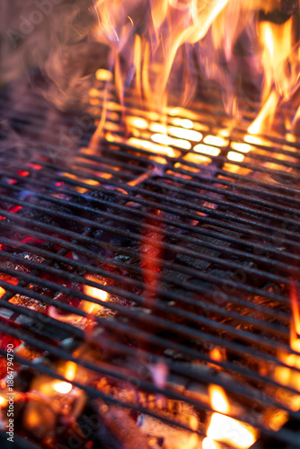 Hot flaming charcoal barbecue grill with glowing fire flames and smoke for outdoor cooking