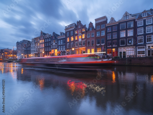 Foto Iconic Amsterdam canals and traditional Dutch architecture at twilight with warm city lights reflecting in the water