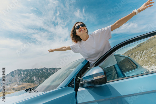 Woman with arms up having fun, car travel concept