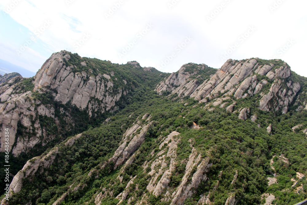 Fototapeta premium Rocky peaks of Montserrat with historic chapels and churches perched among the cliffs, in Catalonia, Spain, taken in July 2024.